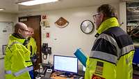Drei Männer in gelben Warnwesten im Gespräch
