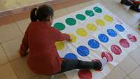 Ein Kind sitzt auf dem Fußboden und spielt Twister.