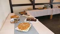 Ein leckeres Kuchenbuffet steht auf einer langen Tischtafel bereit.
