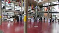 Mehrere Personen stehen in einem großen Foyer und reden miteinander.