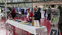 Personen holen sich Informationen wie z.B. Flyer, Bücher und Fachzeitschriften am Informationsstand.