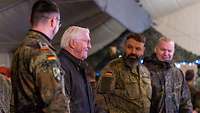 Bundespräsident Frank-Walter Steinmeier steht zwischen drei Soldaten