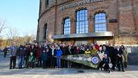 Eine Personengruppe steht vor dem Planetarium für ein Gruppenbild.
