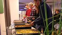 Mehrere Personen stehen an einem Buffet.
