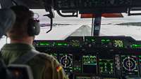 Blick über die Schulter des Kommandanten aus Cockpit auf verschneite Landebahn