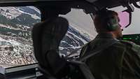 Blick seitlich aus dem Cockpit bei Kurvenflug über teilweise schneebedecktes Hügelland