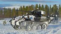 Ein kleines Kettenfahrzeug mit einer 20-Millimeter-Maschinenkanone fährt im Schnee.