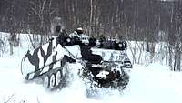 Ein gepanzertes Kettenfahrzeug springt durch den Schnee