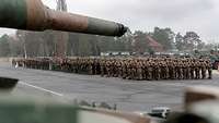 Auf einem Appellplatz in Polen sind zahlreiche Soldaten angetreten. Eine Kanone ragt ins Bild.