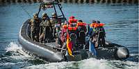 Soldaten fahren mit Zivilisten in einem Speedboot.