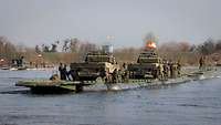 Panzer auf einer Fähre setzen über einen Fluss.