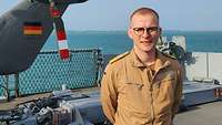 Auf dem Flugdeck einer Fregatte steht ein Soldat vor einem Helikopter