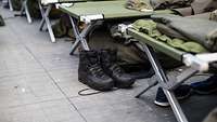 Kampfstiefel vor einem Feldbett