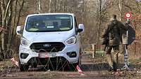 Checkpoint-Ausbildung auf dem Standortübungsplatz Nienburg Ein weißer Van hält an einer Absperrung aus Stacheldraht. Ein Soldat mit Winkerkelle geht darauf zu.