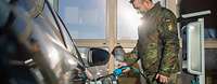 Ein Soldat lädt ein Elektrofahrzeug vom Fuhrpark der Bundeswehr