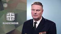 Ein Soldat im Porträt während eines Interviews. Im Hintergrund das Logo der Bundeswehr.