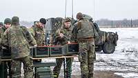 Auf einem Übungsplatz stehen mehrere Soldaten vor einem Tisch, auf dem Behälter platziert sind