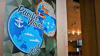 Ein olivgrünes Roll-up mit zwei großen Aufschriften: Pacific#en Waves#en und Pacific#en Skies#en.