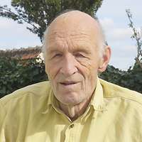 Ein alter Mann im gelben Hemd blickt in die Kamera.