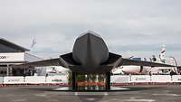 In the exhibition space stands an anthracite-colored aircraft model with a cockpit implied.