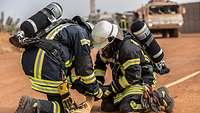 Zwei Feuerwehrmänner verbinden zwei Enden des Feuerwehrschlauches miteinander