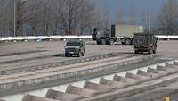 Two trucks and a car are driving on uneven concrete surfaces