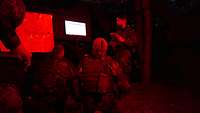 Zwei knieende Soldaten und ein stehender Soldat schauen auf einen Bildschirm. 