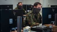 Zwei Soldaten sitzen vor Monitoren.