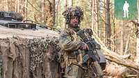 Ein Soldat steht im Kampfanzug vor einem Schützenpanzer Marder