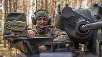 Ein Soldat mit Headset und Tarnschminke blickt aus der Kommandantenluke eines Schützenpanzer Marder