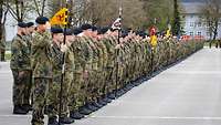 Hunderte Soldaten stehen in Formation mit ihren Verbandswimpeln auf einem betonierten Appellplatz.