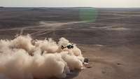 A lot of dust is being whirled up while an H145M is hovering over a desert.