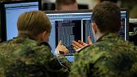Zwei Soldaten sitzen vor einem Monitor.