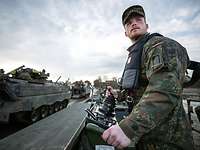 Ein Soldat steht an einem Bedienstand auf einem Boot und schaut seitlich in eine Richtung