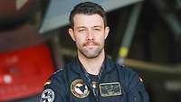 Ein Pilot mit Anti-G-Anzug im Profil, im Hintergrund ein Eurofighter