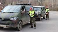 Zwei Militärpolizisten kontrollieren je ein Fahrzeug