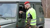 Ein Soldat steht vor einem Fahrzeug und prüft die Identität des Fahrers