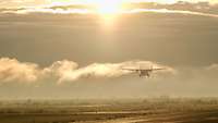 Im Schein der Morgensonne landet ein Flugzeug auf einer Landebahn in der Wüste