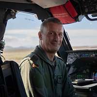 Ein Mann in Fliegerkombi sitzt im Cockpit eines Flugzeugs.