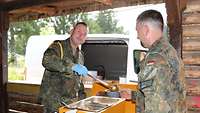 Ein Soldat teilt einem anderen Soldaten eine Mahlzeit aus