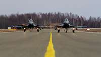 Zwei Flugzeuge vom Typ Eurofighter fahren nebeneinander auf einer Rollbahn