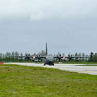 Ein großes Militärflugzeug mit vier Propellern von vorn auf der Landebahn.