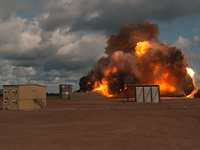 Explosion Eine Feuerwolke breitet sich über einem Feld aus. Ein Gebäude steht davor.