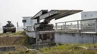 Ein Brückenlegepanzer Leguan klappt seine Legebrücke aus, dahinter steht ein Schützenpanzer am Rand