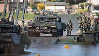 Gewässerüberquerung dank Schwimmschnellbrücke Mehrere Kampfpanzer vom Typ Leopard A7 befahren eine Schnellschwimmbrücke