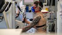 Ein Mann sitzt auf einem Ergometer und ist mit Sensoren verkabelt
