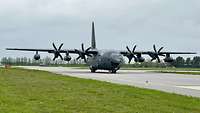 Large military aircraft with four propellers on the runway, front view