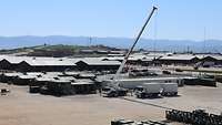 Grüne Zelte, Bundeswehrmaterial und weiße Bürocontainer werden mittels Kran an ihren Platz gestellt
