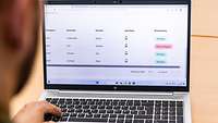 Ein Mann sitzt vor einem Laptop und sichtet eine Tabelle mit Verfügbarkeiten