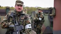 Zwei bewaffnete Soldaten laufen zwischen Containern Streife